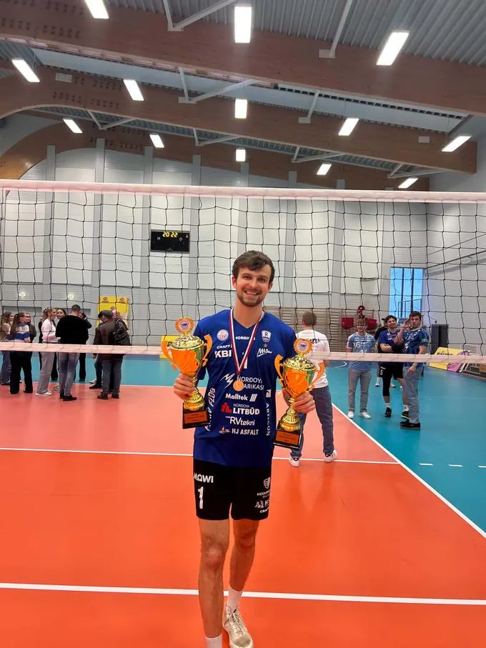 Alain Pineault on court holding two trophies after the season